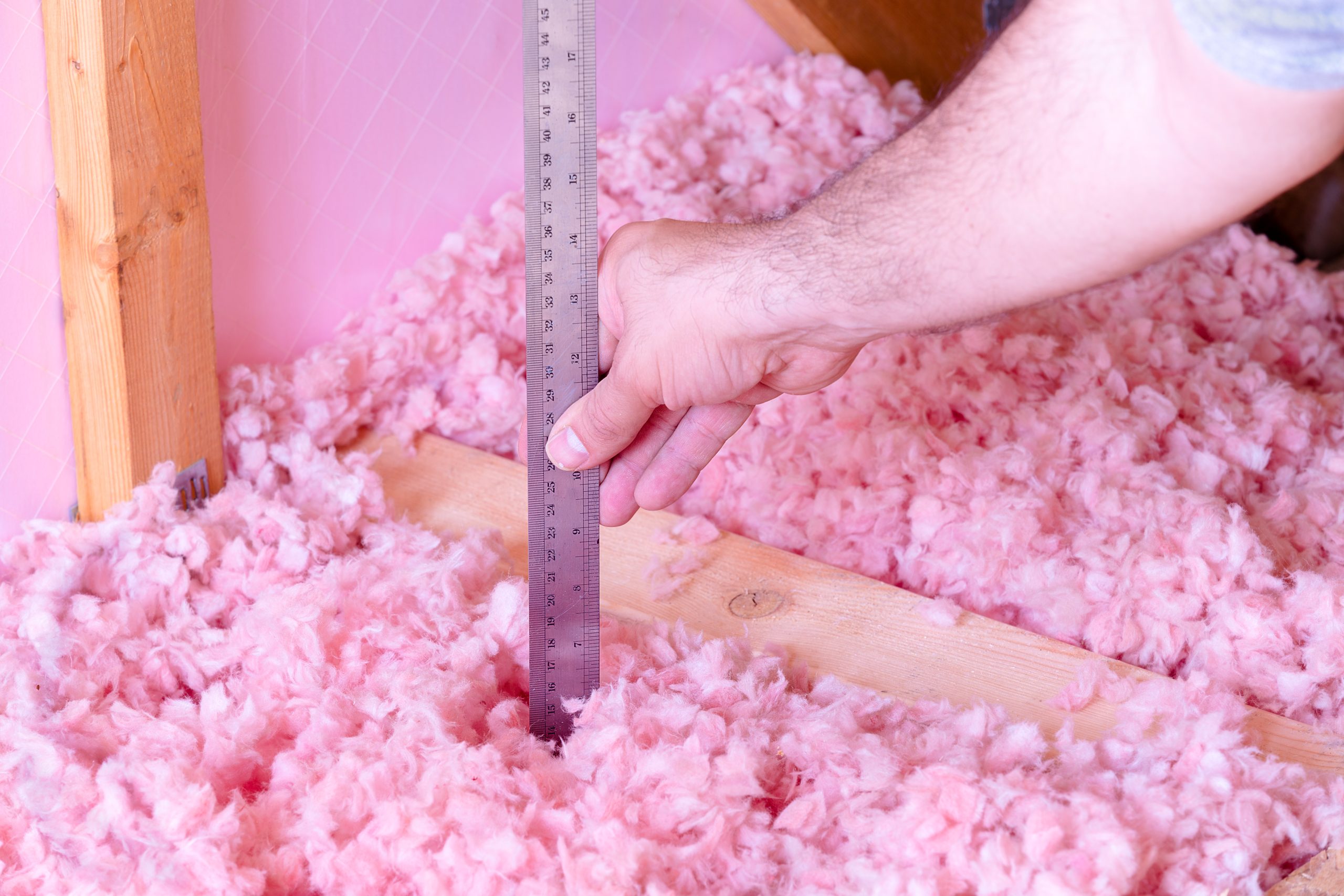 Man Measuring Fiberglass Blown in Insulation