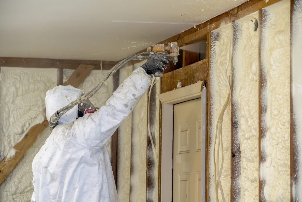 Man spraying Spray Foam Insulation into wall cavity.
